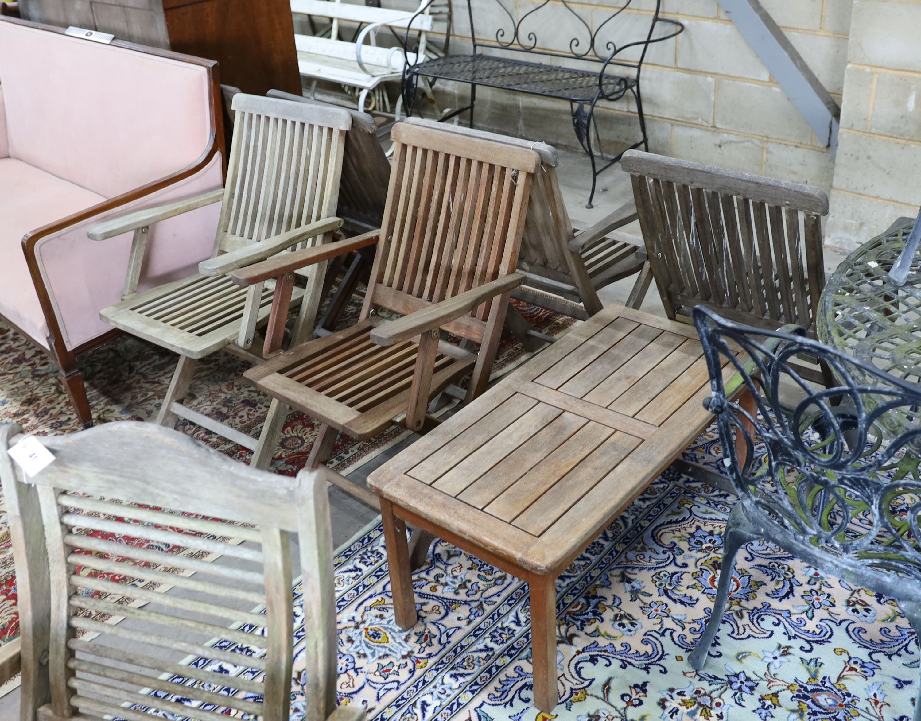 A set of six weathered teak folding garden armchairs and a low teak garden table